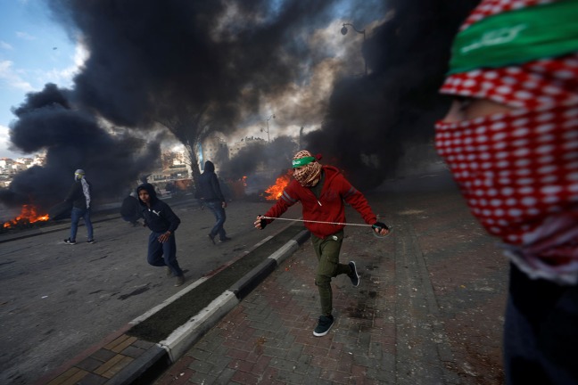 Palestinian protesters run during clashes with Israeli troops at a protest against U.S. President Donald Trump's decision to recognize Jerusalem as the capital of Israel, near the Jewish settlement of Beit El, near the West Bank city of Ramallah